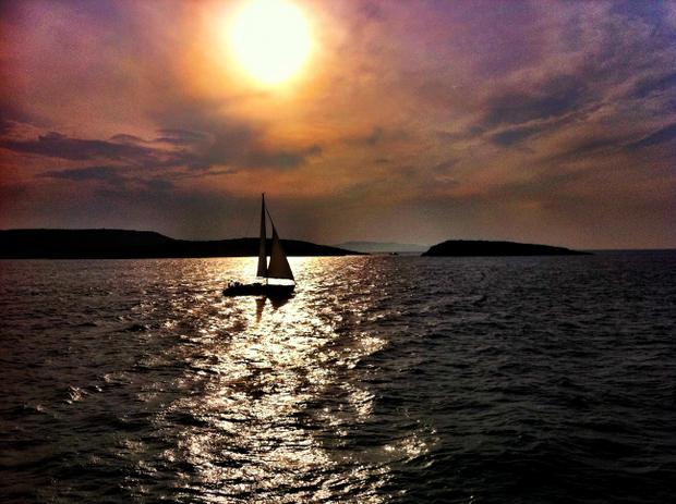 Sunset with a sailboat seen from a small ship cruise in Greece.
