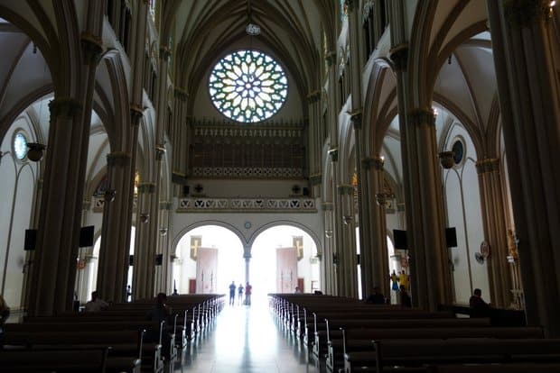 Interior of the cathedral with high vaulted ceilings, pillars and pews lining the floor of the church in Guayaquil.