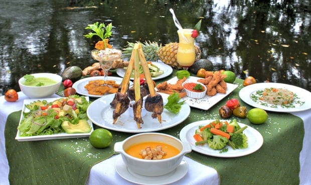 Table of Costa Rican food set outside next to water.
