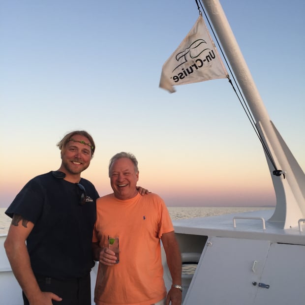 Happy Baja travelers posing in front of the Uncruise flag on the deck of the small ship cruise.