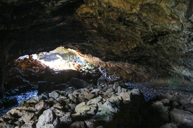 A cave with a light coming through the other side of the cave.