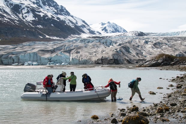 Guests on a skiff excursion from their small ship to the shore in Alaska to walk by the glacier.
