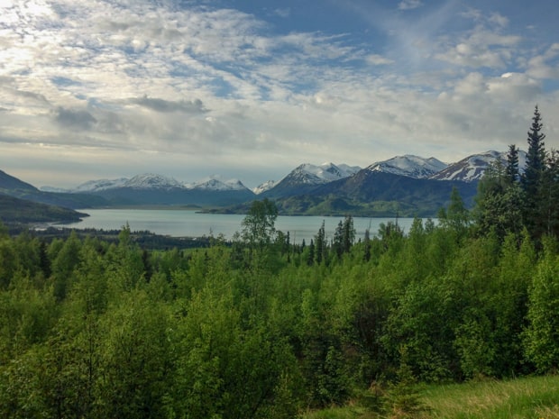 Scenic landscape of Alaskan wilderness, snow capped mountains surrounding a lake.