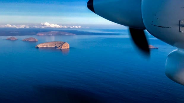 View from a plane of the ocean and crescent shaped islands in the Galapagos.