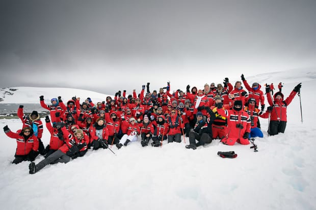 Group from a small cruise ship in Antarctica wearing their red polar expedition parkas on the snow.