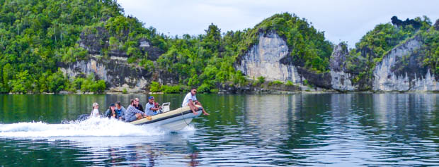 Guests taking a skiff off a small ship cruise to explore islands in Indonesia.