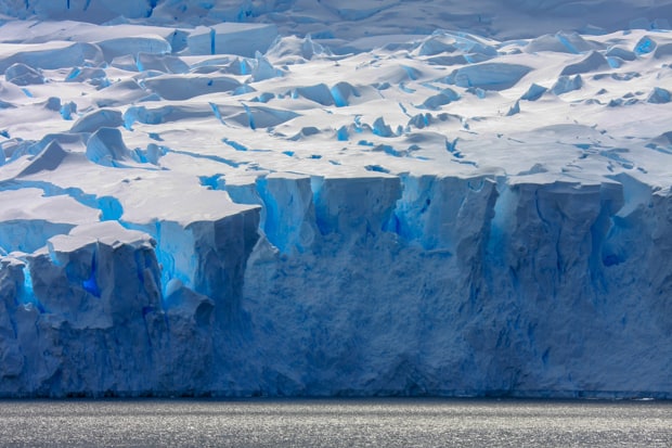 Shades of blue and white on a large ice shelf in Antarctica seen from a small ship.