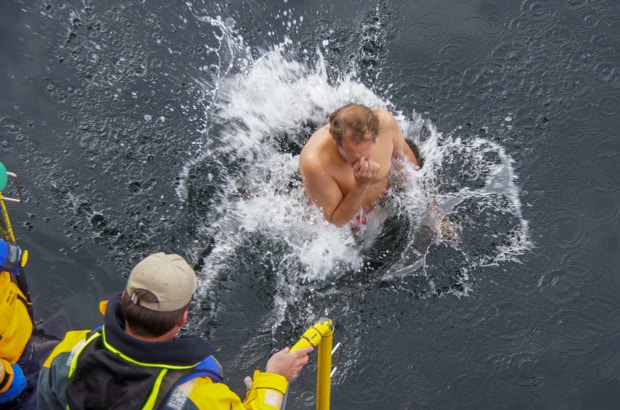Man jumping into the water in Antarctica from his small ship during a polar plunge event.