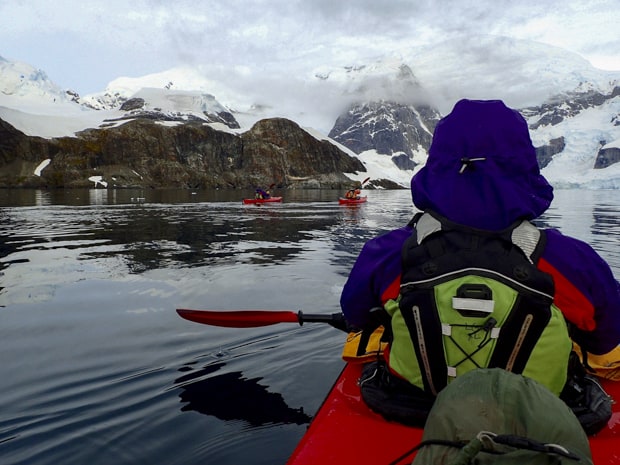 Guests from small ship cruise kayaking close to land in Antarctica.