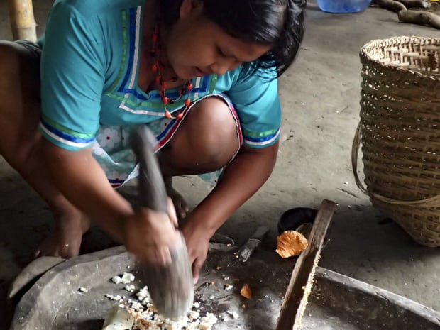 A aboriginal woman making a meal in a large native stone pan.