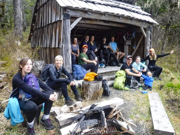 Guests from a small ship cruise sit with their guides to rest while on a Three Lakes Hike in Alaska.