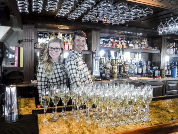 Bartenders smiling and standing behind the lounge bar aboard S.S. Legacy small ship cruise in Alaska.