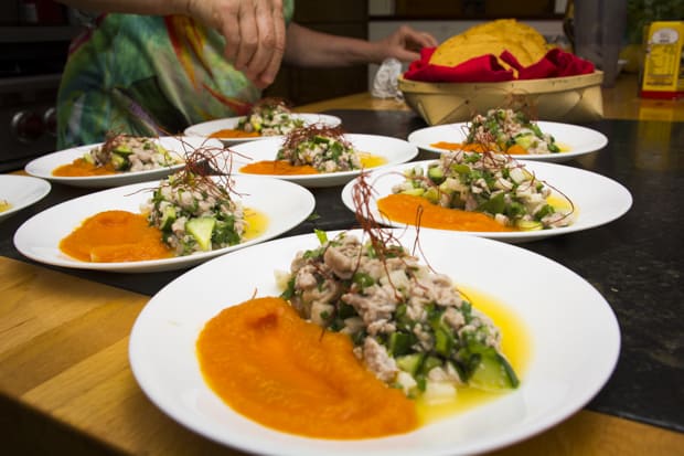 Plates of fresh ceviche and sauce on a table with the chef.