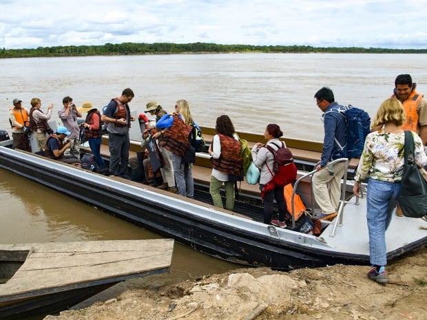 A group of people boarding a motorized canoe on the Peruvian Amazon jungle.