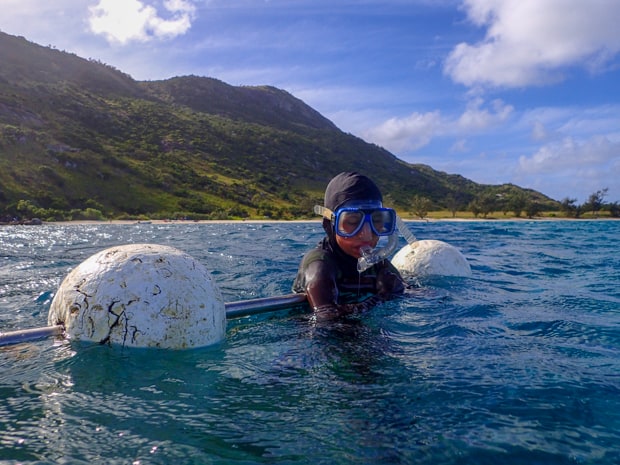 A child in snorkel gear holding on a float taking a break from snorkeling on a small ship cruise.