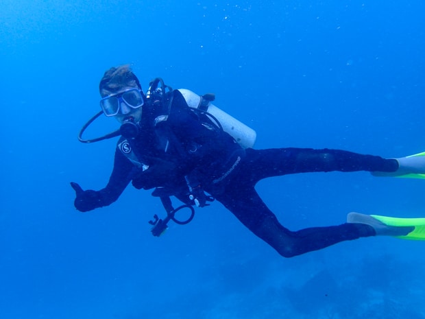 A scuba diver giving a thumbs up while swimming through the Great Barrier Reef.