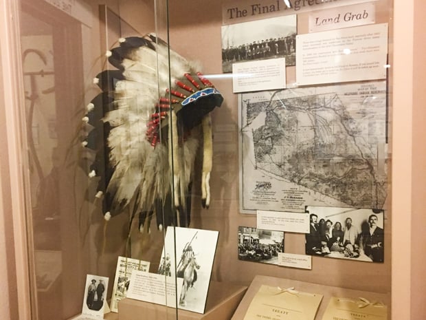 A glass showcase at the Nez Perce county Historical Society museum showing a native american headdress and old pictures.