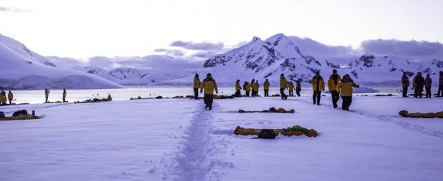 People walking in the pathway created in the snow on Antarctica to get around their campsite for the night.