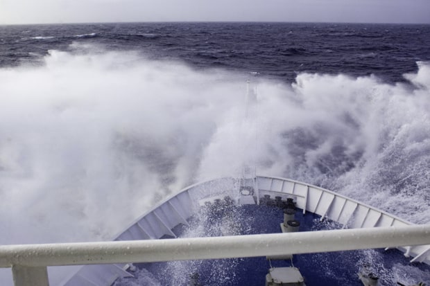 The rough seas splashing over the bow of a small cruise expedition ship during the Drake Passage returning from Antarctica.