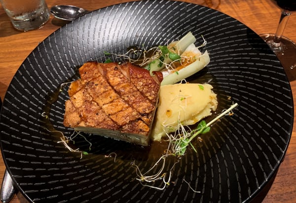 Dinner plate aboard Coral Adventurer, grilled fish with pineapple on a black plate