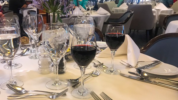 a table with white table cloth and red wine glasses at the restaurant aboard hebridean sky polar expedition ship