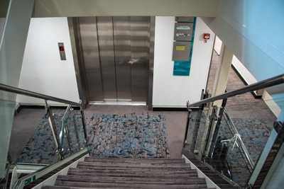 From the top of a set of stairs looking down at the metal doors of the Greg Mortimer's on board elevator.