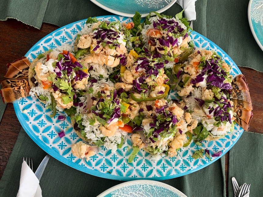 In Belize, a meal of rice, fresh lobster and vegetables served for dinner on top of a teal and white decorated plate.