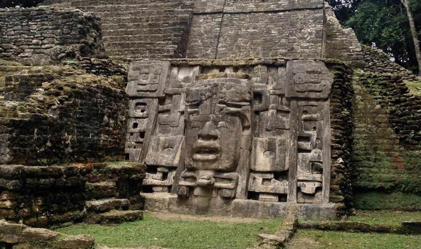 The Mask Temple, a Maya temple and civilization structure at the archaeological site in Belize with limestone walls featuring a mask with facial features.