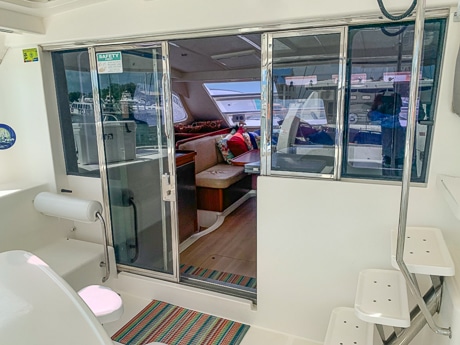 From outside on the back deck of a Belize catamaran looking through sliding glass doors at the inside dining salon.
