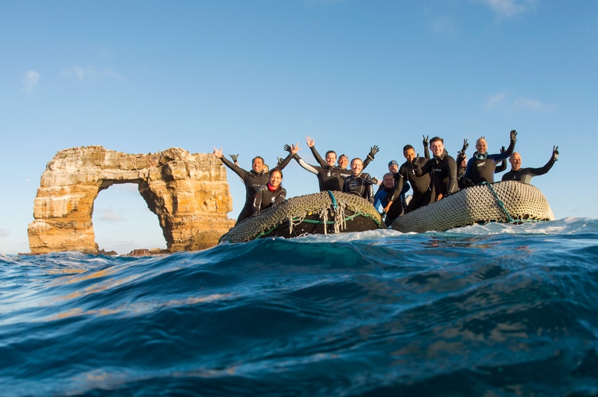 Scuba divers from the Galapagos Sky pose next to Darwins's Arch offshore Darwin Island, Galapagos, Ecuador.