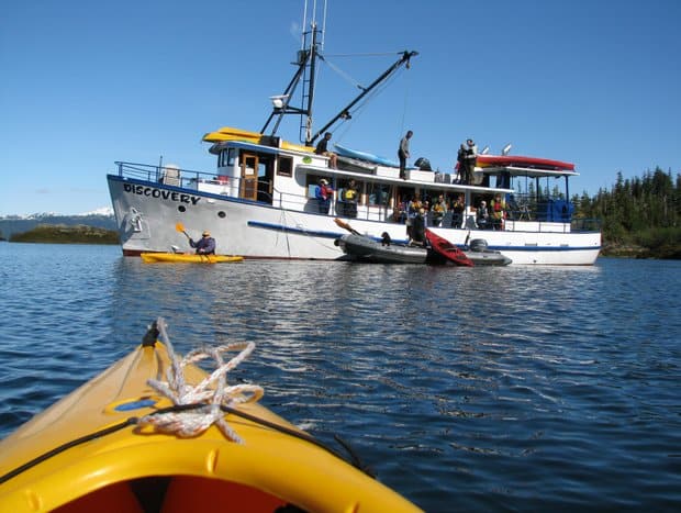 People getting into kayaks off a small ship in Alaska.