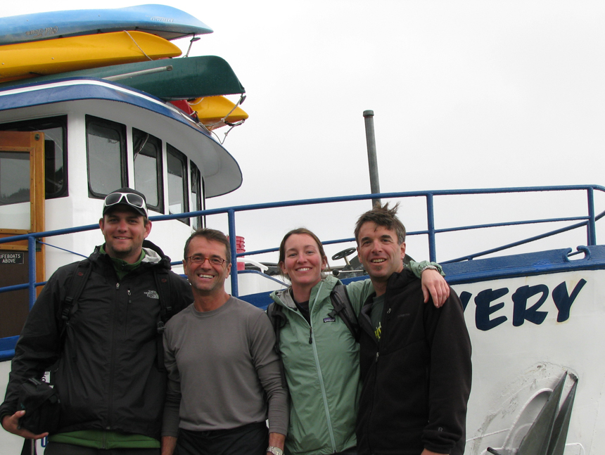 A group of people standing at the bow of the small ship Discovery.