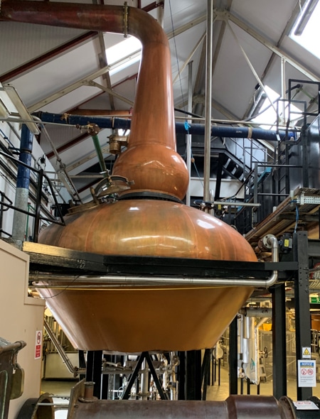 Seen at a whiskey distillery while on an an activity excursion aboard the Classic Scotland Barge Cruise, a large shiny brass machine used in the distilling process of whiskey.