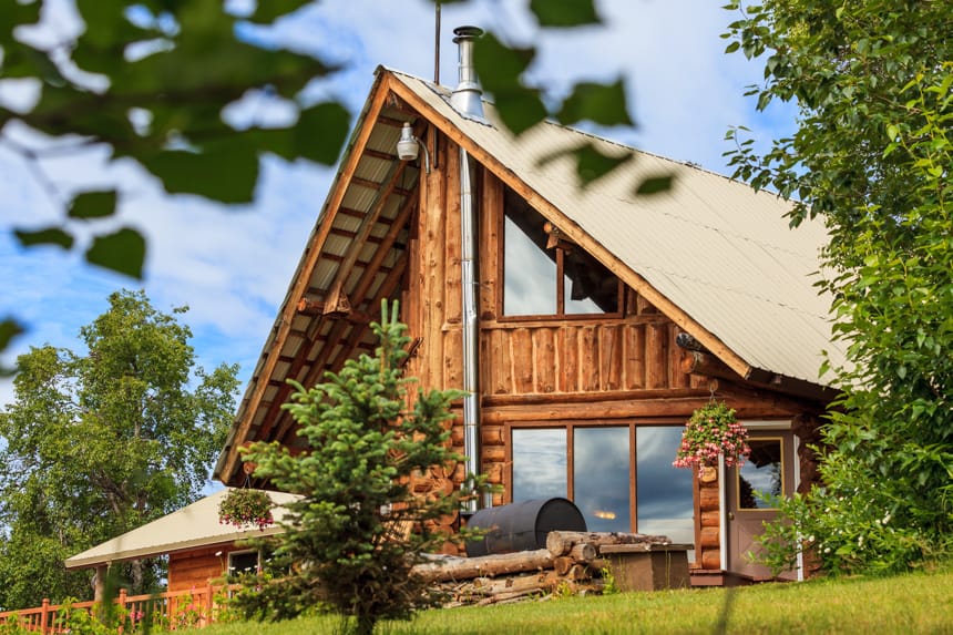 The main building of Winterlake Lodge , and a frame log cabin surruonded by trees