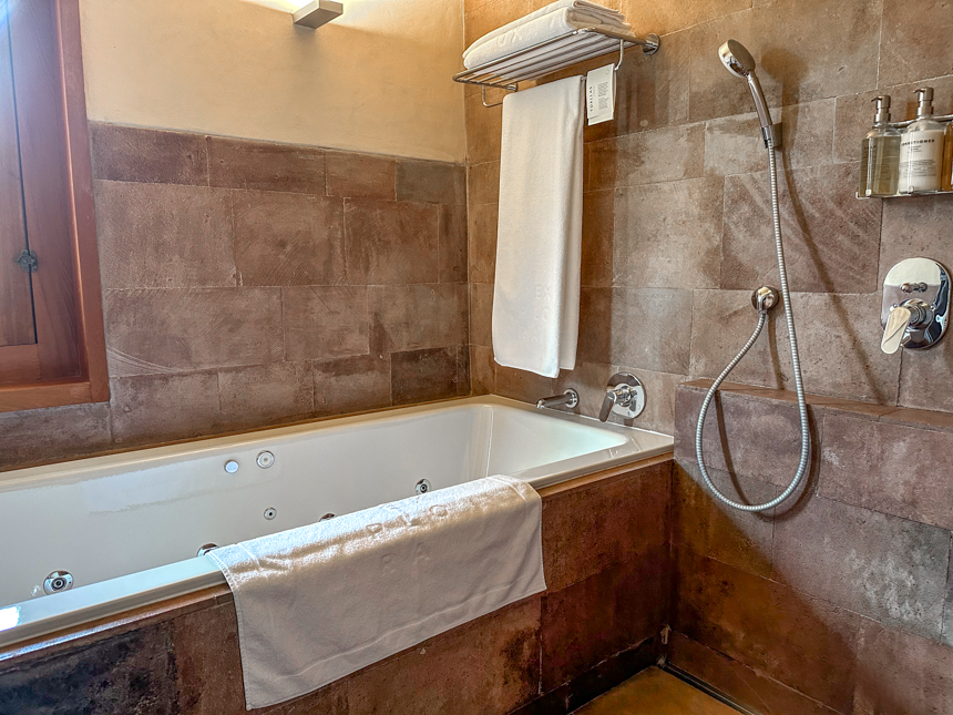 Standard bathroom at Explora Sacred Valley a jacuzzi tub next to a shower with a picture window,