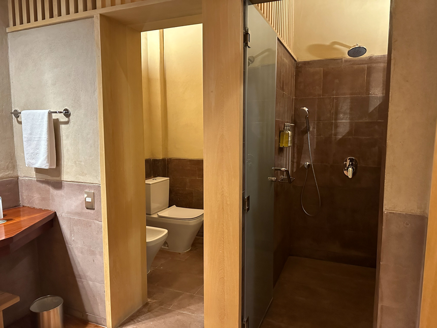 Explora Sacred valley lodge suite bathroom. Separate rooms for toilets and shower, with light wood and warm tan and red tiles