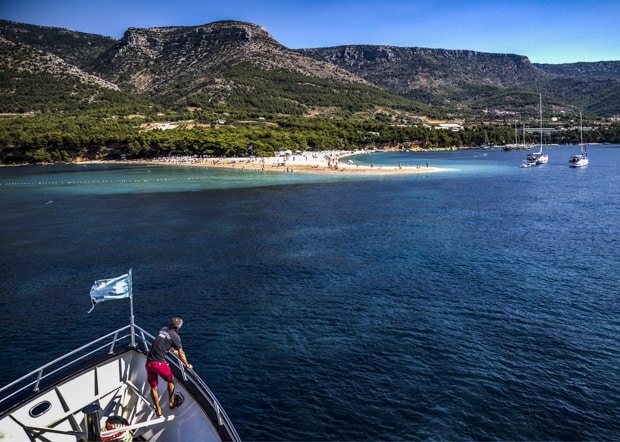 Bow of small ship in front of beach in Croatia.