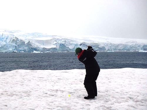 SMall ship passenger swinging a golf club on the snow in Antarctica.