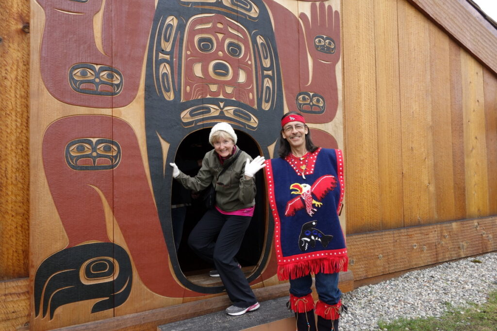 A female traveler seen at the threshold of a tribal house in Alaska with a man in traditional dress