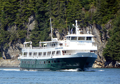 UnCruise reviews 76-guest Wilderness Discoverer in Alaska with painted green hull and white upper decks.