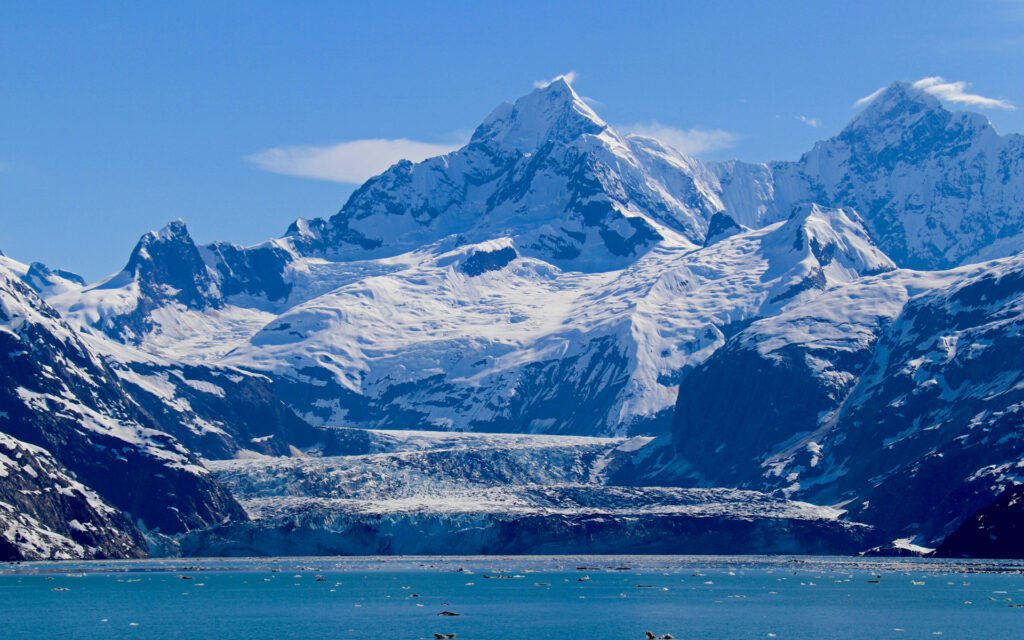 Ice and snow covered peaks with a large tidewater glacier terminating in Johns Hopkins Inlet in Glacier Bay National Park, Alaska