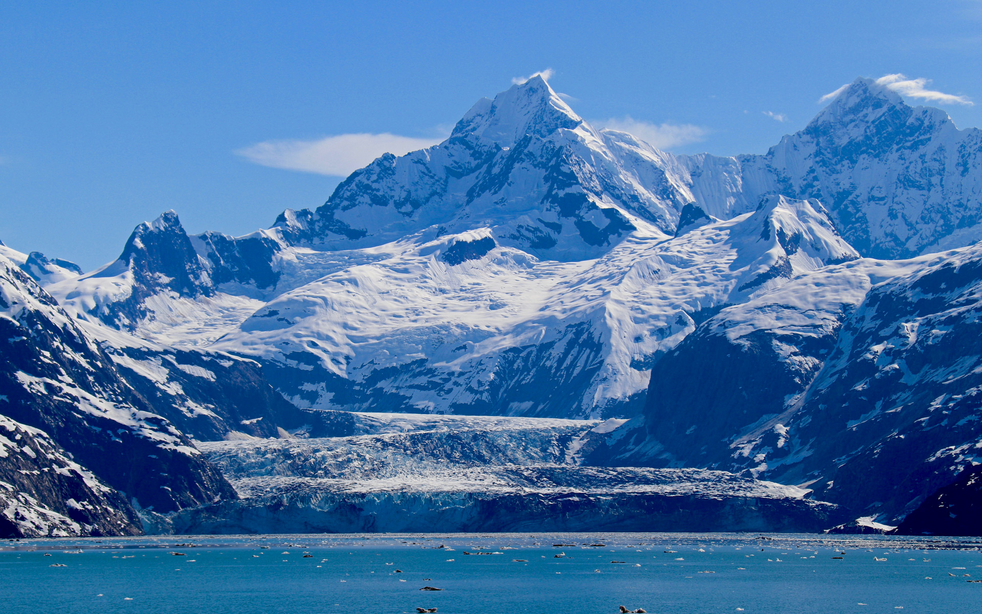 Ice and snow covered peaks with a large tidewater glacier terminating in Johns Hopkins Inlet in Glacier Bay National Park, Alaska