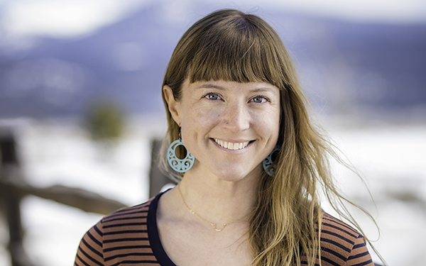 A portrait of Lis Larson with bangs and brown hair in a striped brown shirt
