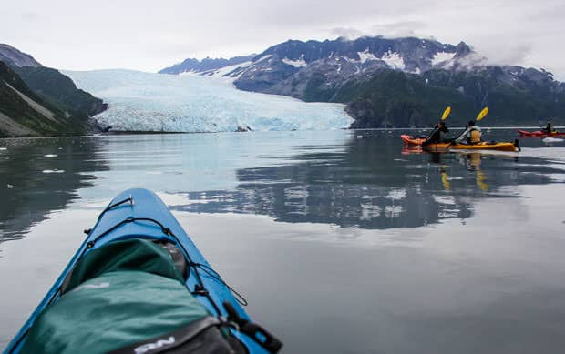 The bow of a blue kayak seen as it approaches a glacier in Kenai Fjords National Park