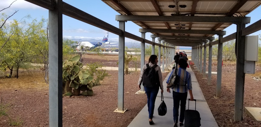 Travelers walking on a covered walkway at the Galapagos airport.