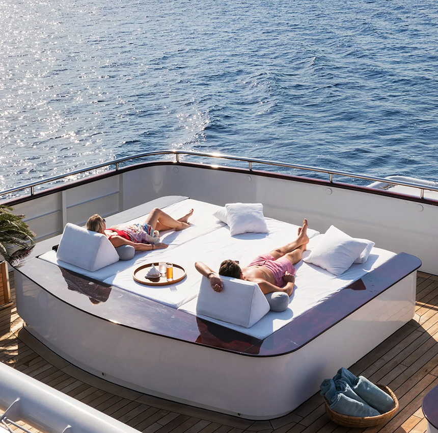 Couple laying out in their swimsuits, enjoying the day beds on a small ship cruise