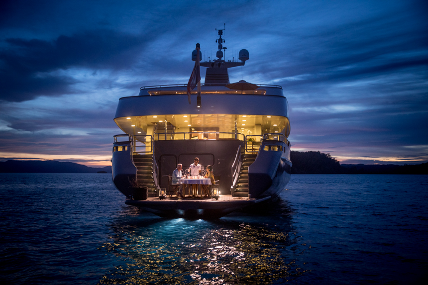 A couple enjoying a romantic dinner as the sunsets on the back of the swim platform aboard a small ship cruise.