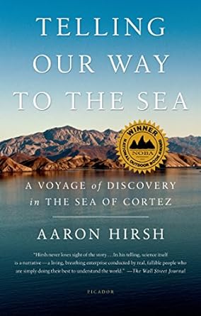 Book cover of Telling Our Way to the Sea by Aaron Hirsh showing brown desert mountains of Baja rising out of a calm blue sea and blue sky above.