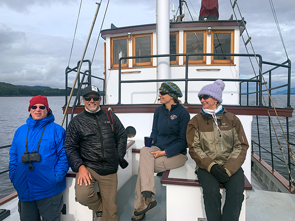 Four travelers on the bow of a small ship cruise in Alaska