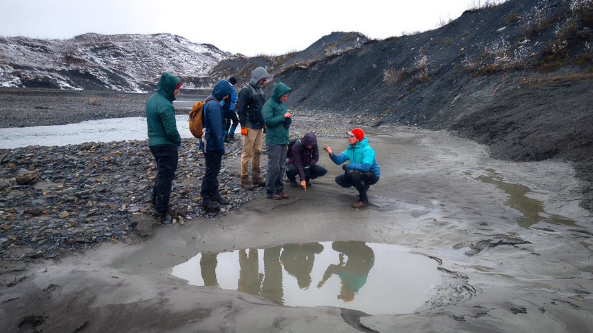 Group of hikers in rain gear pointing out rocks on a wet rainy day